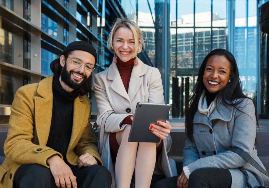 business-colleagues-looking-at-camera-and-smile-while-sitting-on-the-stairs-outside-the-office-e1656221977504.jpg